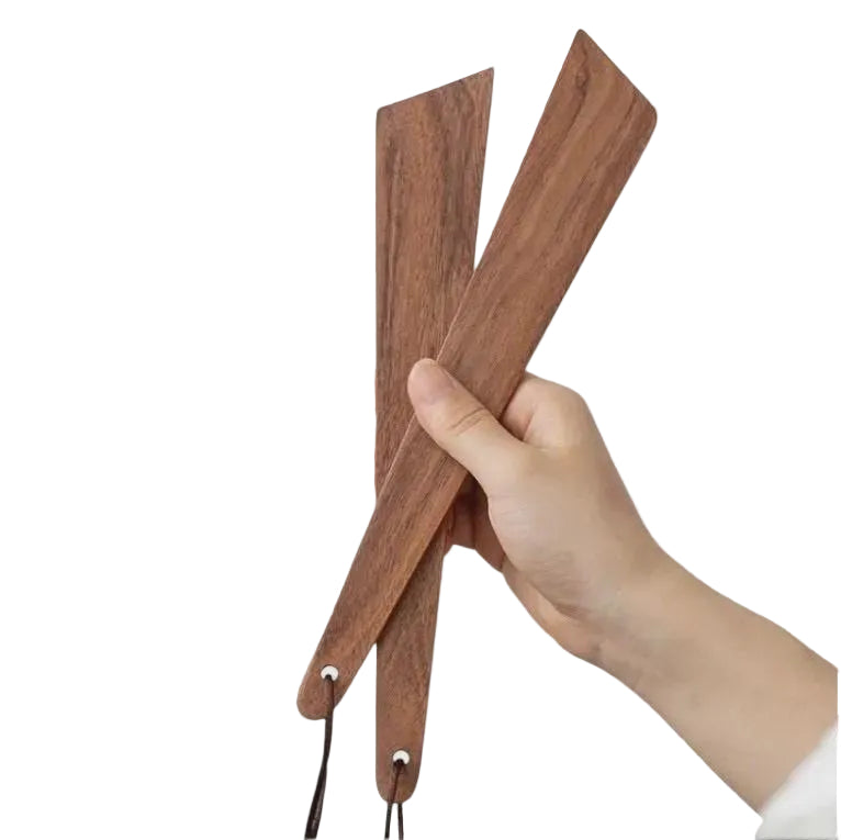 Hand holding a wooden paddle against a light gray background