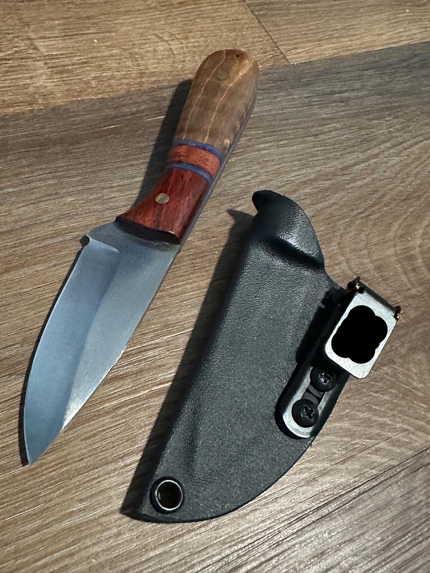Knife with wooden handle and sheath on a wooden surface